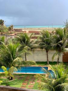 un complejo con piscina y palmeras en Apartamento com vista para o mar, piscina , deck , playground e estacionamento ., en Taíba