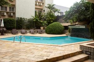 una piscina en un patio con sillas y un edificio en Caruaru Pallace Hotel, en Caruaru