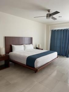 Un dormitorio con una cama grande con ventilador de techo. en MARENA Suites & Apartments, en Mazatlán