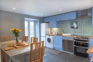 una cocina con armarios azules y una mesa con comedor. en Finest Retreats - Court Cottage en East Buckland