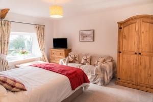 ein Schlafzimmer mit einem Bett und einer Couch und einem Fernseher in der Unterkunft Finest Retreats - Court Cottage in East Buckland