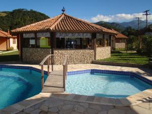 - une piscine avec un kiosque dans la cour dans l'établissement Pousada Chalés Vista da Serra, à Visconde de Mauá