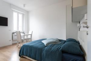 een slaapkamer met een bed met een blauwe deken en een tafel bij Al 32 Apartment in Milaan