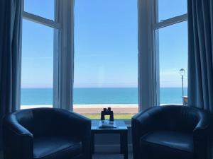 two chairs and a table in a room with a view of the ocean at Bromwell Court in Llandudno