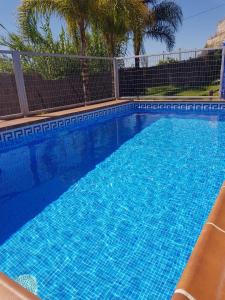 een groot blauw zwembad met een hek en bomen bij Casa cecilio in Nerja