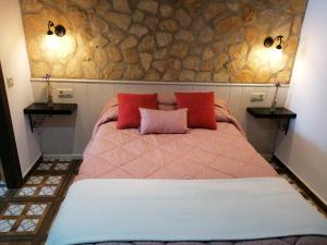 a bedroom with a large bed with two red pillows at La Casa de Abajo in Setenil