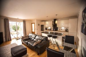 een woonkamer met een leren bank en een keuken bij Langley Cottage with patio, spacious rooms - part of Langley Serviced Apartments several properties in Wick in Wick