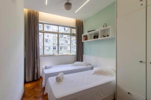 two beds in a room with a window at Apartamento 3 quartos Ipanema in Rio de Janeiro