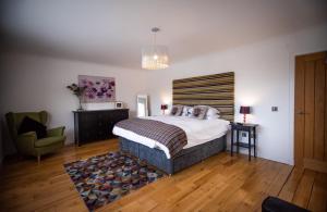 een slaapkamer met een groot bed en een stoel bij Langley Cottage with patio, spacious rooms - part of Langley Serviced Apartments several properties in Wick in Wick