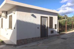 ein weißes Gebäude mit einer Tür und einem Zaun in der Unterkunft Sunsetsunrisecilento in Caprioli