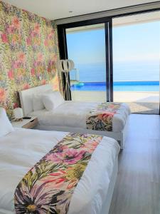 two beds in a room with a view of the beach at Villa Brava Atlântico in Ribeira Brava