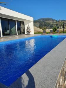 a swimming pool with blue water in front of a house at Villa Brava Atlântico in Ribeira Brava