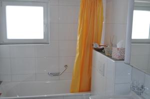 Ruhe pur في Aeschi bei Spiez: حمام مع ستارة دش برتقالية وحوض استحمام