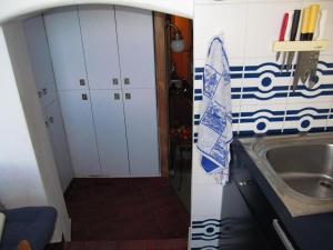 una pequeña cocina con fregadero y una cocina con armarios blancos. en Voce del Mare, en Riomaggiore