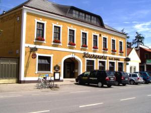 a yellow building with cars parked in front of it at Weinhotel Kirchenwirt in Gols