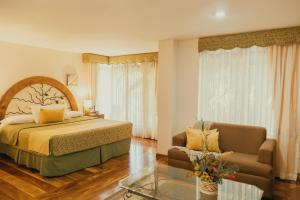 ein Schlafzimmer mit einem Bett, einem Sofa und einem Glastisch in der Unterkunft El Rodeo Estancia Boutique Hotel & Steakhouse in San José