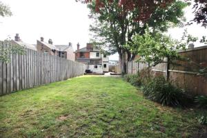 a backyard with a wooden fence and a grass yard at Berrygate in Ipswich