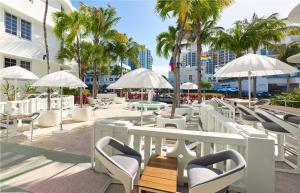 eine Terrasse mit Stühlen, Tischen und Sonnenschirmen in der Unterkunft Axel Beach Miami-South Beach - Adults Only in Miami Beach