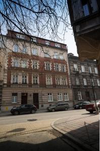 een groot bakstenen gebouw met auto's geparkeerd voor het bij Home in Krakow Silvio's Apartments in Krakau