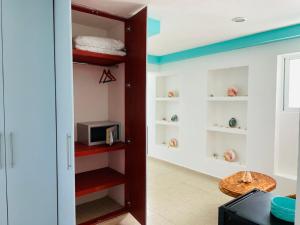 a kitchen with a room with shelves and a microwave at Habitación Amanecer Turquesa #2 in Isla Mujeres