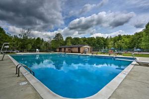a large blue swimming pool in front of a house at Arrowhead Lake Home with Game Room and Beach Access! in Pocono Lake