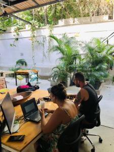 a man and a woman sitting at a table with a laptop at Santuario Getsemani Hostel in Cartagena de Indias