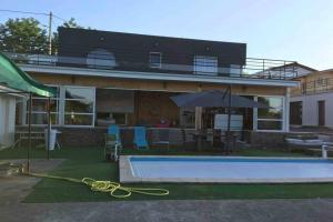 a house with a swimming pool and an umbrella at Koh Samet Siam Manahakhon Appart & Spa in Rieux-de-Pelleport