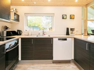 a kitchen with black and white cabinets and a sink at 12 person holiday home in Hals in Hals