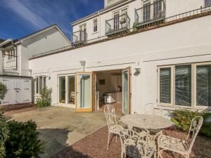 Un patio con una mesa y sillas frente a una casa. en 2 Garden Apartment, en Kingsbridge