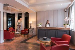 a woman standing behind a bar in a lobby with red chairs at Hôtel de Genève in Paris