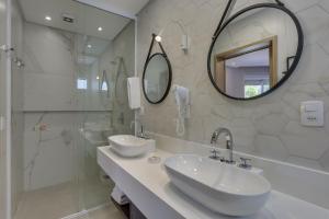 un bagno bianco con due lavandini e una doccia di Hotel Sete Ilhas a Florianópolis