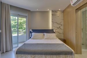 una camera da letto con un letto e una grande finestra di Hotel Sete Ilhas a Florianópolis