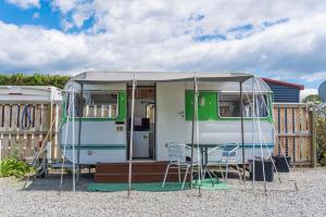 a green and white caravan with a table and chairs at Leithfield Beach Holiday Park in Leithfield