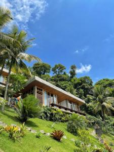 a house on a hill with palm trees and grass at Verde Mar Pousada in Angra dos Reis