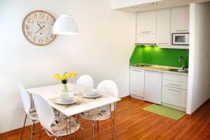 eine Küche mit einem weißen Tisch und Stühlen sowie einer Uhr in der Unterkunft Modern City Apartments in Sarajevo