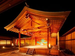 een groot houten podium met 's nachts verlichting bij Yamatoya Honten in Matsuyama