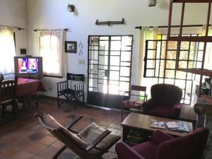 een woonkamer met stoelen en een tafel en een televisie bij Baradero - La vida de campo a una hora del Obelisco! km142 R9 - las chapas casa de campo baradero in Baradero