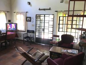 sala de estar con sillas, mesa y TV en Baradero - La vida de campo a una hora del Obelisco! km142 R9 - las chapas casa de campo baradero en Baradero