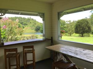 a porch with a wooden table and two windows at CedarBrae Country Stay in Gympie