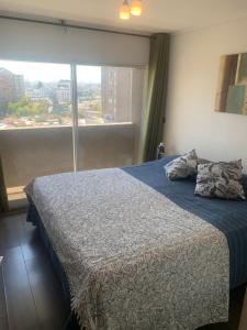 1 dormitorio con cama y ventana grande en Selma Apartment Ñuñoa Best Suite, en Santiago