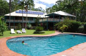 two people swimming in a swimming pool in front of a house at Riviera Bed & Breakfast in Gold Coast