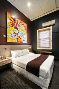 a bedroom with a large bed and a painting on the wall at Tolarno Hotel in Melbourne