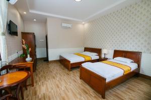 1 dormitorio con 2 camas, escritorio y mesa en Mỹ Khánh Resort, en Can Tho