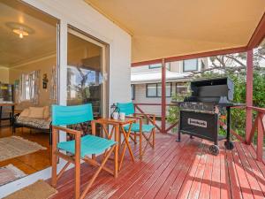 a porch with a grill and chairs and a table at Poppy's Beach House - Beachfront Whangapoua Home in Whangapoua
