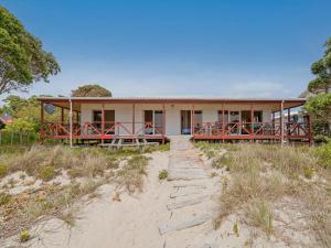 a house on the beach with a path leading to it at Poppy's Beach House - Beachfront Whangapoua Home in Whangapoua