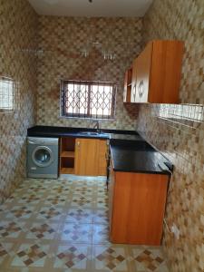 a kitchen with a sink and a washing machine at FANTASTIC APARTMENT, TRAVELER AWARD WINNER 2024, 1 ensuite bedroom, WIFI, air condition, separate living room, 2 toilets, 2 walk in shower rooms, hot water, separate kitchen, restaurant, bar, garden, 24 hour security, 20 minutes airport, North Legon Accra in Accra