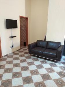 a black leather couch in a living room with a tiled floor at FANTASTIC APARTMENT, TRAVELER AWARD WINNER 2024, 1 ensuite bedroom, WIFI, air condition, separate living room, 2 toilets, 2 walk in shower rooms, hot water, separate kitchen, restaurant, bar, garden, 24 hour security, 20 minutes airport, North Legon Accra in Accra