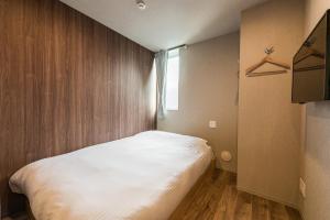a small bedroom with a large white bed in it at &AND HOSTEL ASAKUSA KAPPABASHI in Tokyo