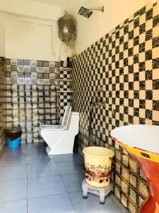 a tiled bathroom with a toilet and a sink at Whoopers Hostel Kasol in Kasol
