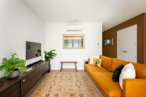 a living room with a yellow couch and a tv at The Nest Central Christchurch in Christchurch